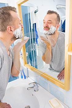 Guy shaving his beard in bathroom
