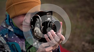 The guy is shooting with an old movie camera. Adjusts the focus ring