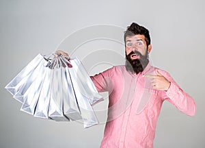 Guy shopping and pointing at bags. Recommendation concept. Hipster on surprised face recommends to buy. Man with beard