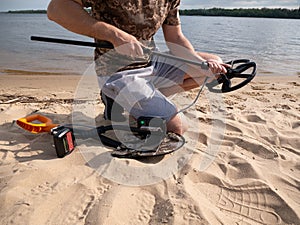 Guy on the shore getting ready for a treasure hunt with a metal detector