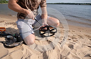 Guy on the shore getting ready for a treasure hunt with a metal detector