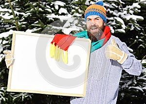 Guy shows thumb up with firtrees covered with snow. photo