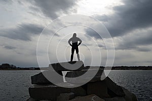 Guy Silhouetted in a Super Hero Pose on a Rock Jetty