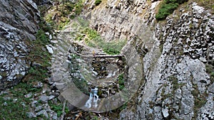 The guy is sitting on a big tree above the river.