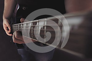 A guy is sitting on a black background playA guy is sitting on a black background playing an electric guitaing an electric guitar.