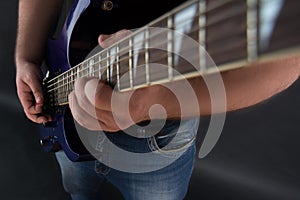 A guy is sitting on a black background playA guy is sitting on a black background playing an electric guitaing an electric guitar.