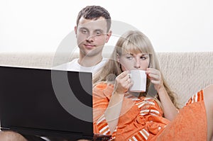 The guy sitting with his laptop on the couch, sitting next to a girl with a Cup of tea