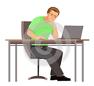 Guy is sitting at table. Young handsome handsome boy at computer. Upset. In jeans, T-shirt and sneakers. Tired. Single