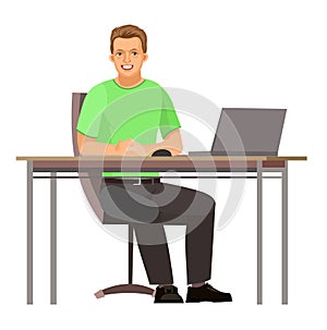 Guy is sitting at table. Young handsome handsome boy at computer. Works. Friendly smile. In jeans, T-shirt and sneakers