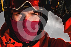 guy in ski goggles adjusts them on his face and wearing a protective helmet, close-up. A male skier has the sun shining