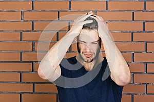 Guy with slight bristle in dark blue tshirt hold hands on head. Macho exhausted because of suffering from headache. Body