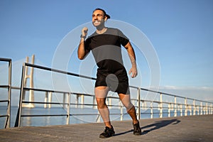 guy in sportswear warms up by seaside preparing for jog