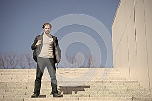 Thoughtful young man sitting on steps against blue sky background