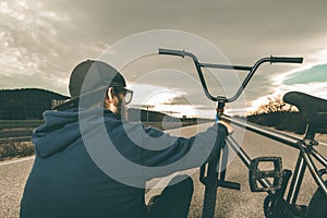 Guy standing bmx bike. BMX rider with and a sunset. Extreme urban sports