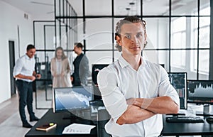 Guy standing in front of people. Team of stockbrokers works in modern office with many display screens