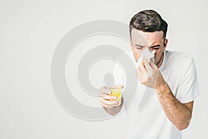 A guy standing on the right side of a frame in white t-shirt is holding a handkerchief in one hand for sneezing at the