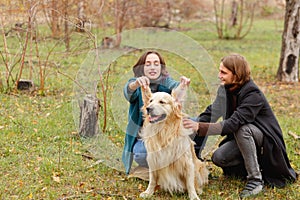 The guy is stroking the dog and the girl raised her ears in the woods for a walk