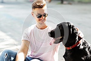 Guy in sunglasses hugs his dog in autumn park