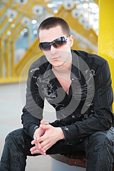 Guy in sunglasses sits on footbridge
