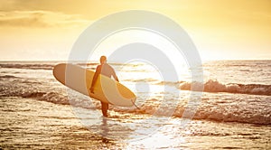 Guy surfer walking with surfboard at sunset in Tenerife - Surf concept