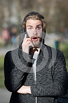 Guy with surprised face talk on smartphone in park, communication