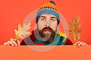 Guy with surprised face wears warm hat on orange background