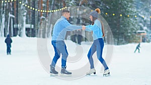 Guy in sweater tries to amaze girl on outdoor ice rink