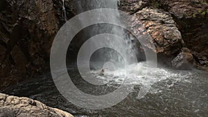 Guy Swims in River Pool at Waterfall Foot in Park