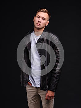 A guy in a T-shirt and black leather jacket and looks with a serious look.