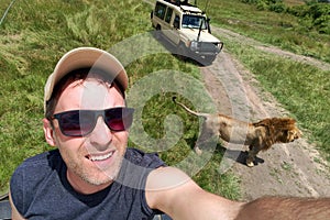 guy takes a selfie with a wild lion during an African safari in nature. A man is photographed with wild animals in Kenya