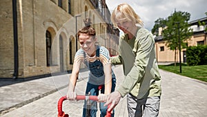 Guy teach and help girlfriend ride bicycle in city