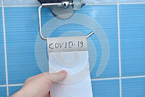 Guy tears off toilet paper with inscription COVID-19