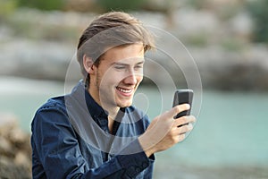 Guy texting on the phone on the beach