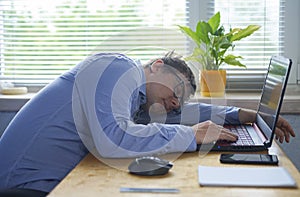 Tired of hard work student guy sleeping on laptop at table