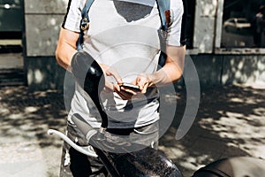 A guy or a tourist activates or rents an electric scooter using a mobile application on a cell phone.