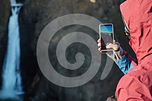 Guy tourist taking pictures of a waterfall in the mountains of I