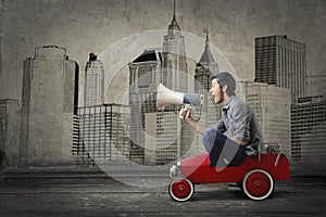 Guy on a toy car screaming in a megaphone