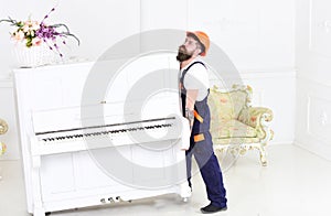 Guy from transportation company moving old piano alone. Tired guy lifting heavy stuff