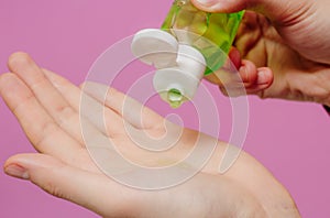 The guy treats his hands with an antibacterial sanitizer. Pink background. Medical content