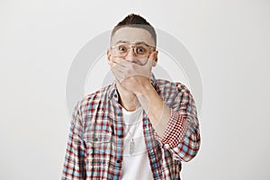 Guy tries to hold laugh on important meeting. Portrait of attractive adult man in glasses chuckling and covering mouth