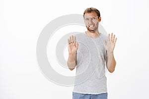 Guy trying refuse proposal being not in mood raising palms in rejection gesture clenching teeth and making sorry