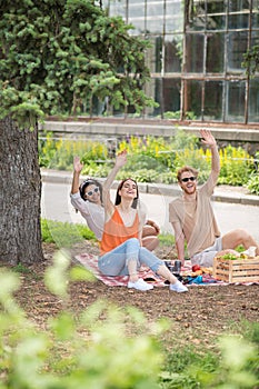 Guy and two girls gesturing affably with hands