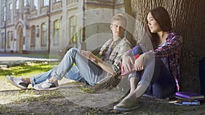 Guy under tree looking at girl sitting next to him, love at first sight feelings