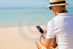 Guy using phone on the beach