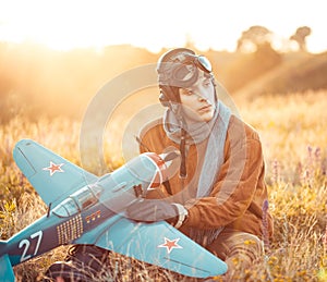 Guy in vintage clothes pilot with an airplane model outdoors