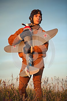 Guy in vintage clothes pilot with an airplane model outdoors