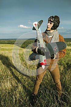 Guy in vintage clothes pilot with an airplane model outdoors