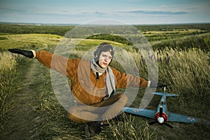 Guy in vintage clothes pilot with an airplane model outdoors