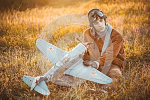 Guy in vintage clothes pilot with an airplane model outdoors