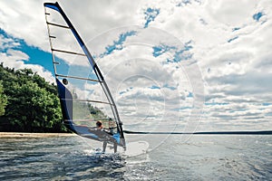 The guy in the waggon swims on the windsurf on lake